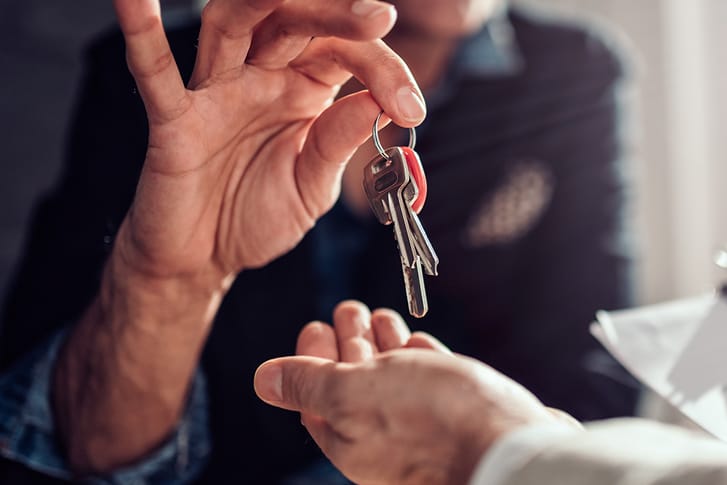 Adult placing a set of house keys in another person's palm.
