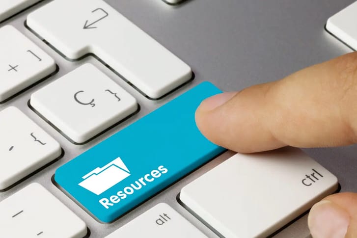 Adult presses the blue "Resources" button on a computer keyboard.